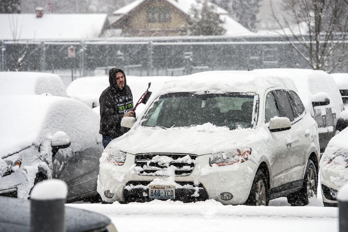 Joe Phipps. assistant principal at John Rogers High School, brushes off over 3 inches of snow from his SUV as he tries to get home for his wife’s birthday, Friday, Dec. 15, 2017, in Spokane, Wash. (Dan Pelle / The Spokesman-Review)