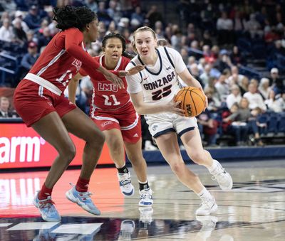 Gonzaga guard Brynna Maxwell (22) dribbles the ball into the key as Loyola Marymount forward Destiny Samuel (11) andt guard Noelle Yancy (21) defend during the first half of a NCAA college basketball game, Thursday, Jan. 26, 2023, in the McCarthey Athletic Center.  (COLIN MULVANY/THE SPOKESMAN-REVIEW)