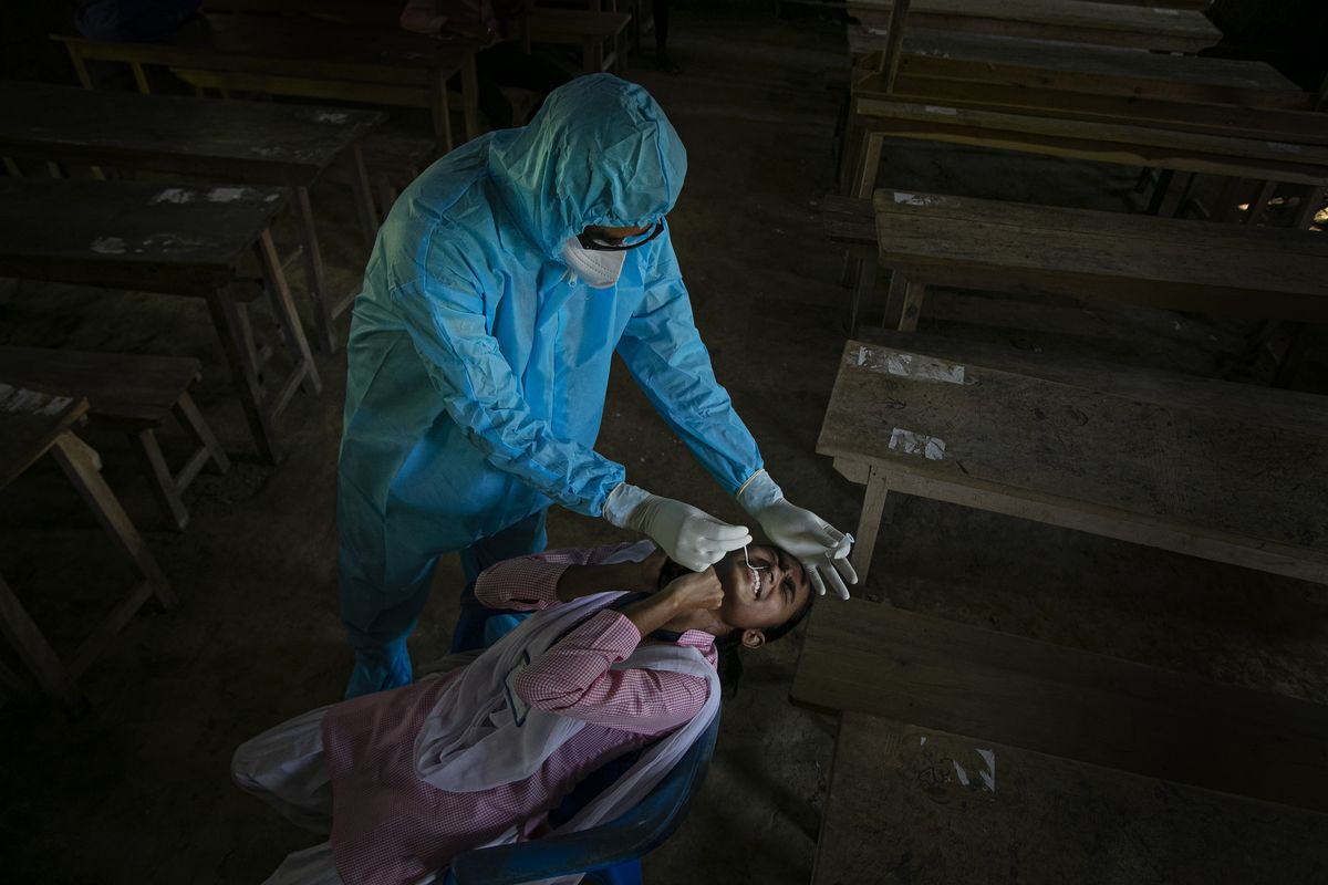 In this Sept. 30, 2020, file photo, an Indian health worker takes a nasal swab sample of a student to test for coronavirus after classes started at a college in Jhargaon village, outskirts of Gauhati, India. The global death toll from COVID-19 has topped 2 million. (Anupam Nath/Associated Press)