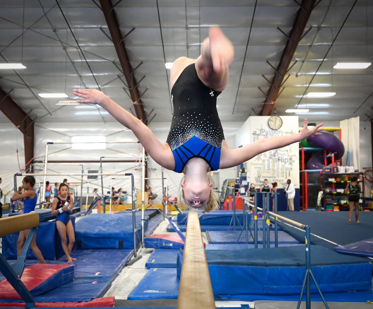 Rylin Zimmerman, 17, performs a challenging move on the balance beam Thursday, July 29, 2021 at Dynamic Gymnastics in north Spokane. Students at the gym talked about how they find the confidence to perform dangerous maneuvers.  (Jesse Tinsley/THE SPOKESMAN-REVIEW)