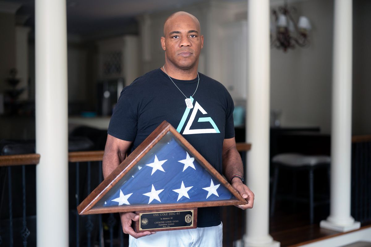 Anton Gunn, whose brother Cherone was killed in the bombing of the USS Cole at age 22, holds the flag that covered his brothers coffin in Columbia, S.C., on Aug. 11, 2023. Families of the sailors who were killed in the bombing and survivors have been making the trek to the war court at Guantánamo Bay for pretrial hearings since 2011. (Sean Rayford/The New York Times)