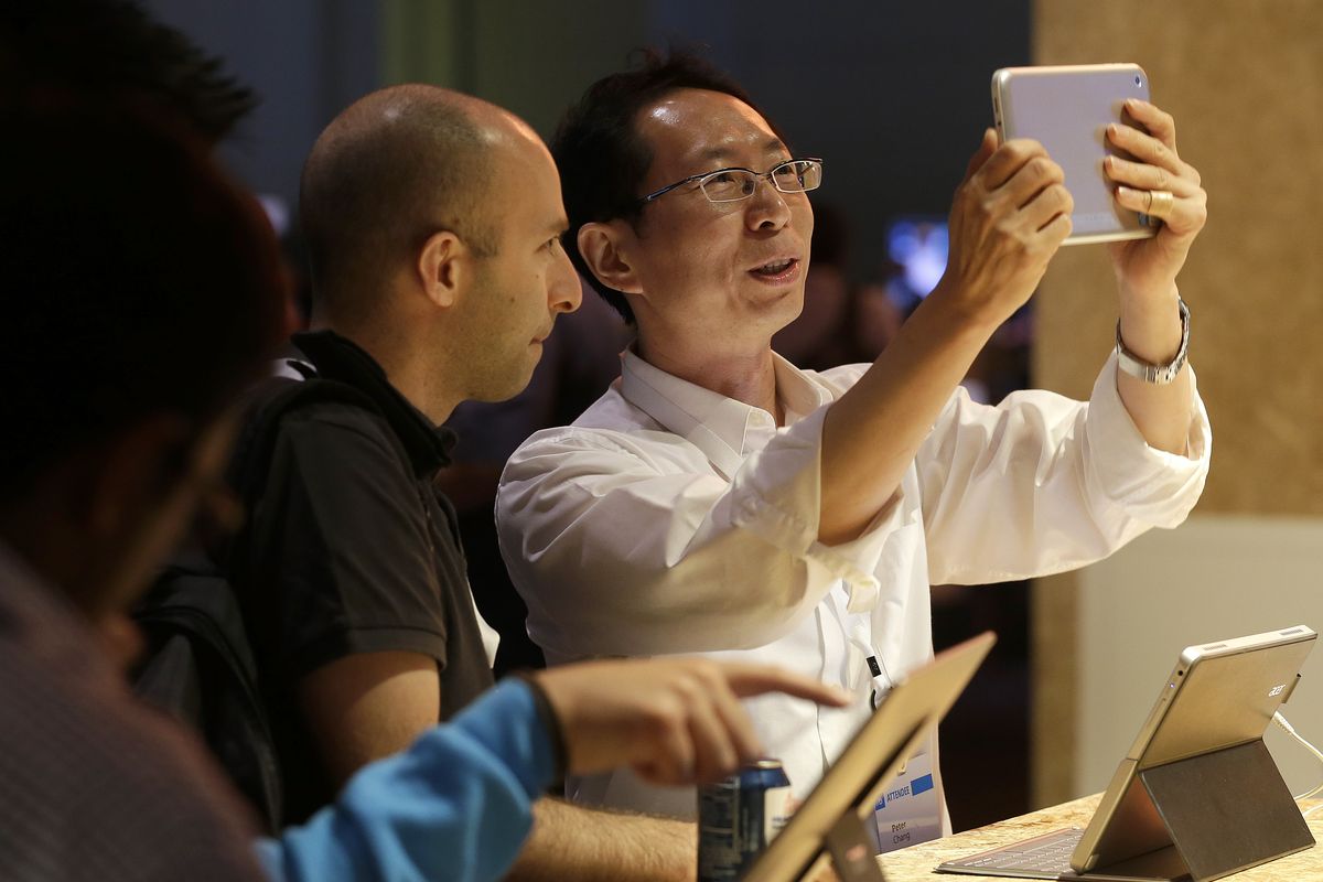 Two men look at the Acer Iconia W3 tablet at a Microsoft event in San Francisco on Wednesday. Microsoft on Wednesday released a preview version of an update to Windows 8, aiming to address some of the gripes people have with the company’s flagship operating system. (Associated Press)