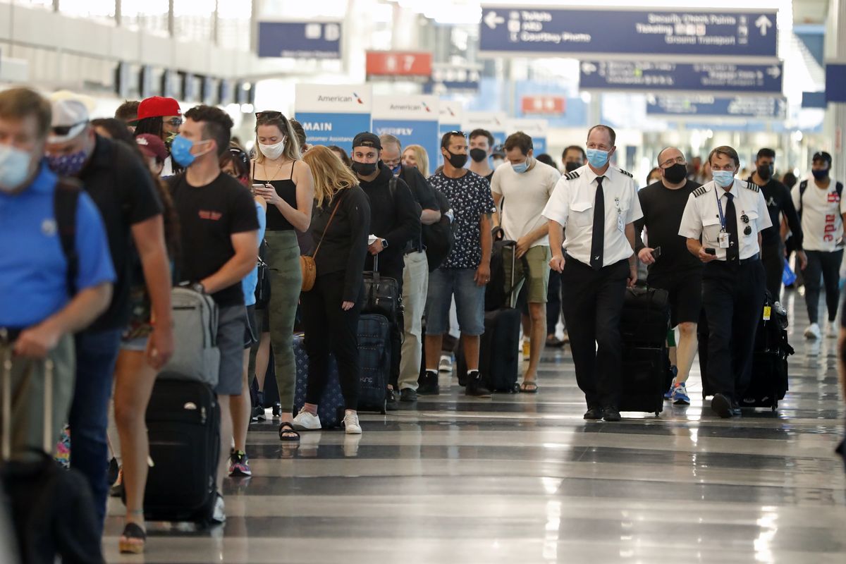 FILE - Two airplane pilots pass by a line of passengers while waiting at a security check-in line at O