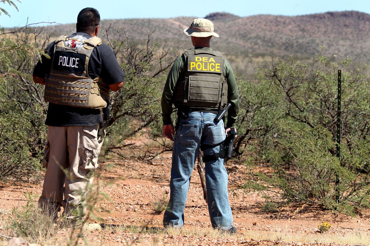 Det. Bill Silva, left, with the Bisbee Police Department, and an unnamed agent with the Drug Enforcement Administration patrol a fence line east of Naco, Ariz., after a Border Patrol agent was killed early Tuesday, Oct. 2, 2012. The shooting occurred after an alarm was triggered on one of the thousands of sensors placed by the U.S. government along the border, and the agents went to investigate, said Cochise County Sheriff
