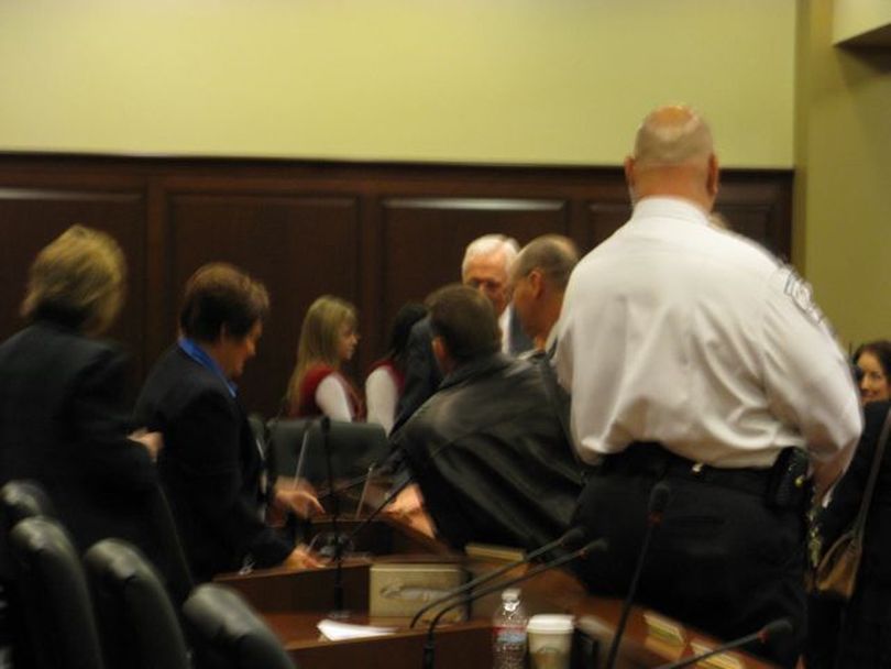 In this blurry photo, angry nullification supporters gather around Sen. Patti Anne Lodge after the Senate State Affairs Committee killed the health care nullification building on a voice vote on Friday morning; one man slammed his hand on the wooden counter in frustration as a security guard, right, joined the group. (Betsy Russell)