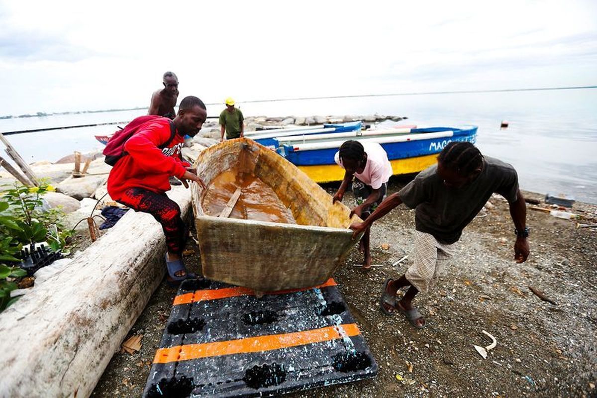 Fishermen lift and secure a small boat along the shoreline as they prepare for the arrival of Tropical Storm Melissa, which is forecast to bring heavy rain and strong winds, in Kingston, Jamaica, October 25, 2025. REUTERS/Octavio Jones (Octavio Jones)