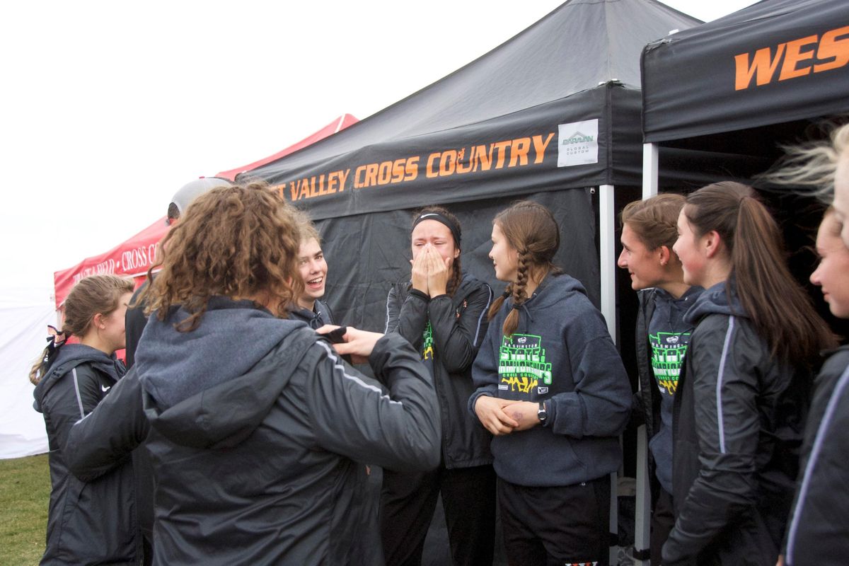 West Valley High cross country runner Emma Garza, center, and her teammates react after their coach, John Moir, announces at the Class 2A state cross country team championship Nov. 3, 2018, the Eagles had won the title. From left, with back to camera is Allie Andrews and Moir, Sydney Stone, Sadie Langford, Garza, Briella Bell, Sarah Adamson, Jenna Engeland and Annika Esvelt. Garza’s finish time was the tiebreaker. (Julie Garza / Courtesy/The Spokesman-Review file photo)