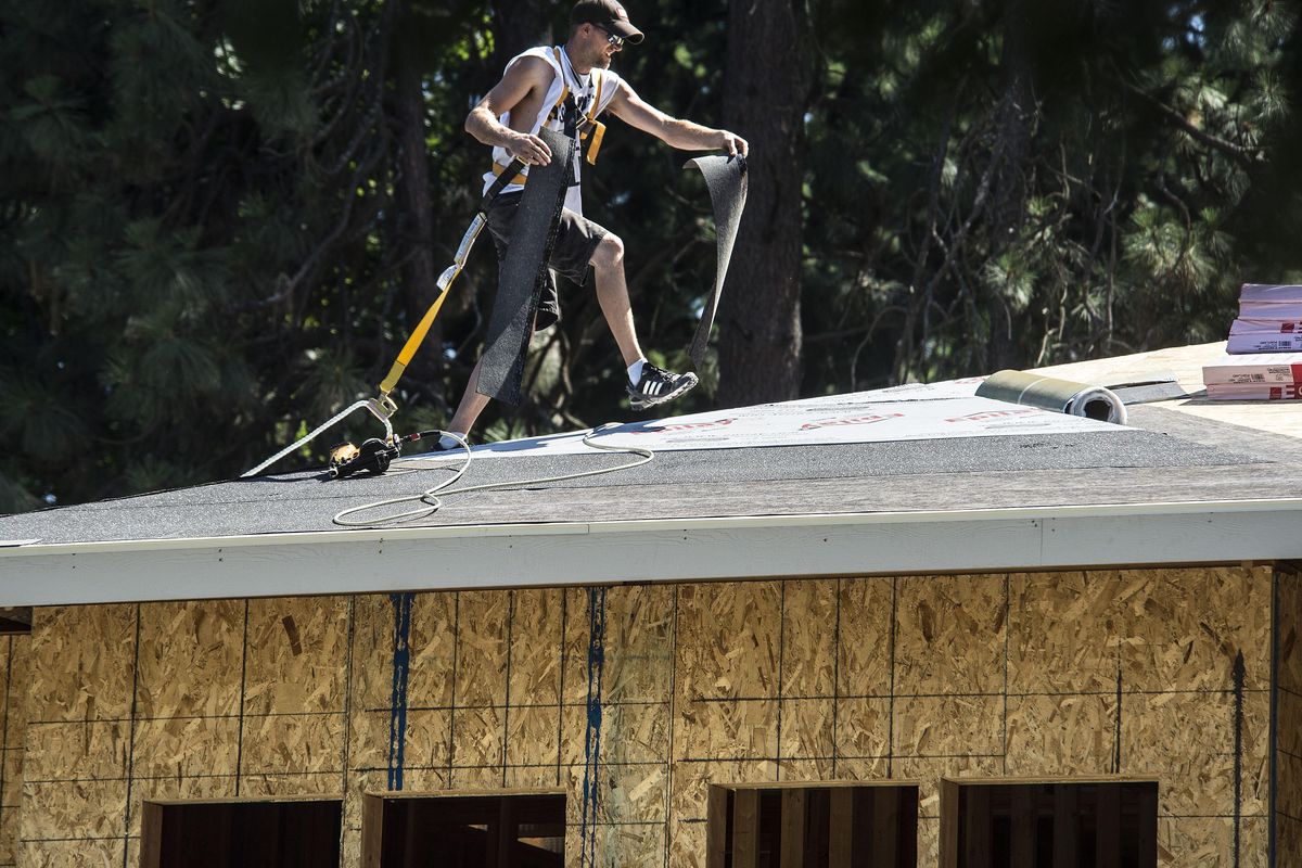 Mike Schanuth shuffles across a roofline with a handful of new shingles at the site of new construction at the corner of 13th Avenue and Lacey, July 6, 2017, in Spokane, Wash. Its like being in a sauna (on the roof) says Schanuth. (Dan Pelle / The Spokesman-Review)