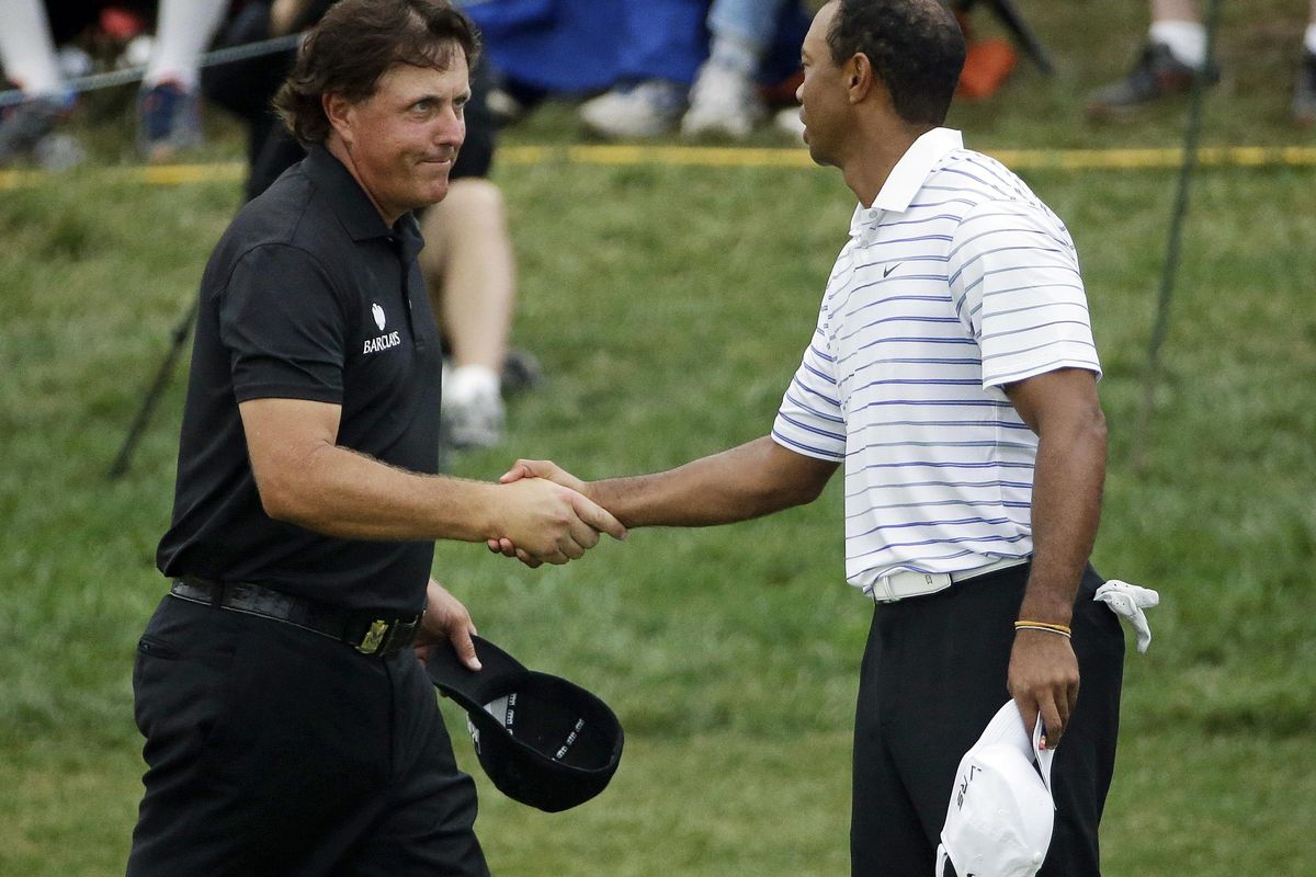 In this Aug. 8, 2014, file photo, Phil Mickelson, left, shakes hands with Tiger Wood after the second round of the PGA Championship golf tournament at Valhalla Golf Club in Louisville, Ky. Woods and Mickelson are in the same group at The Players Championship this week. (David J. Phillip / Associated Press)