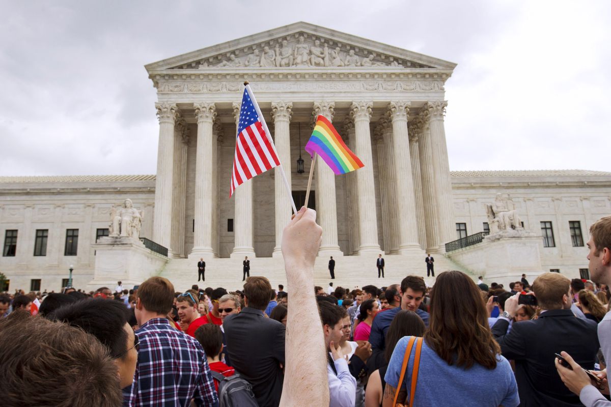 A man holds a U.S. and a rainbow flag in 2015 outside the Supreme Court in Washington after the court legalized gay marriage nationwide. (Jacquelyn Martin)