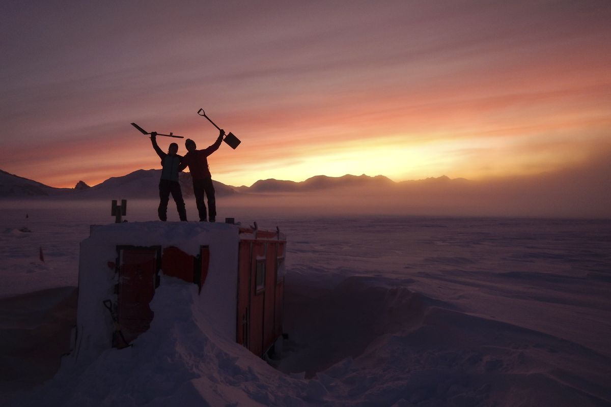 In this handout photo provided by British Antarctic Survey, field guides Sarah Crowsley, left, and Sam Hunt, right, pose for a photo after digging out the caboose, a container used for accommodation that can be moved by a tractor, at Adelaide island, in Antarctica in June.  (Robert Taylor)