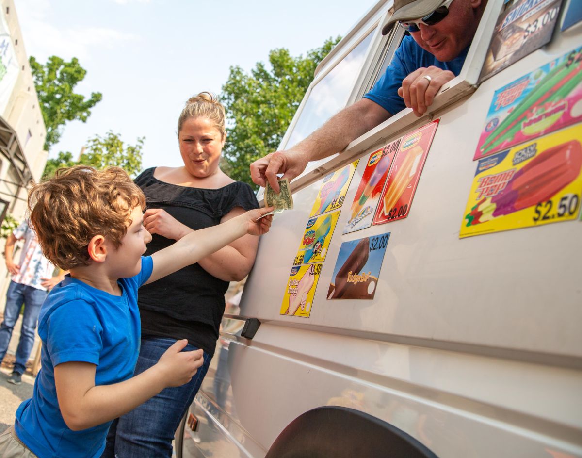 Avery Sohn, 4, gives CC Delivery owner Patrick Gleesing a one dollar bill as payment for his ice cream order on July 31, 2018, while Brandy Shoop assists with his order. Gleesing served 80 children plus daycare helpers out of his Dodge Sprinter ice cream van. (Libby Kamrowski / The Spokesman-Review)