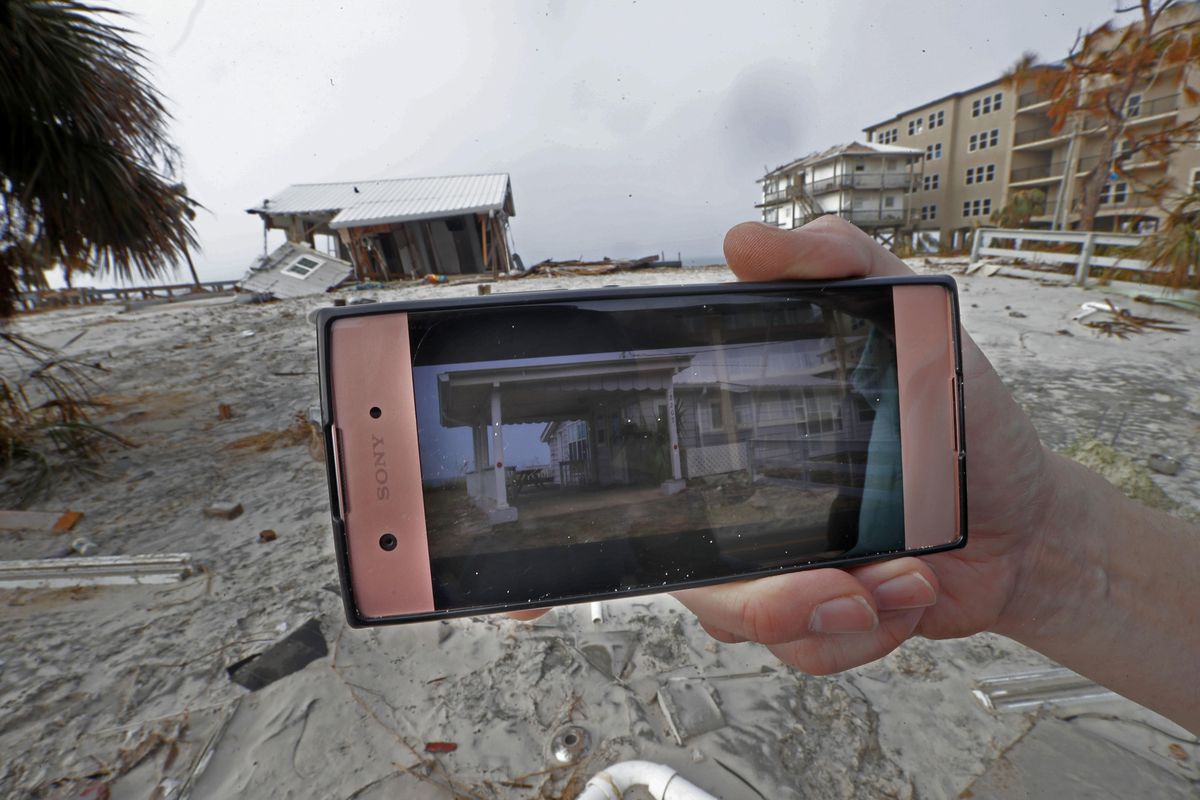 Ron Eden shows a photo of his annual vacation rental, which his family was in before they fled Hurricane Michael just before it hit, in front of the remnants of the home, in Mexico Beach, Fla., Wednesday, Oct. 17, 2018. (Gerald Herbert / Associated Press)