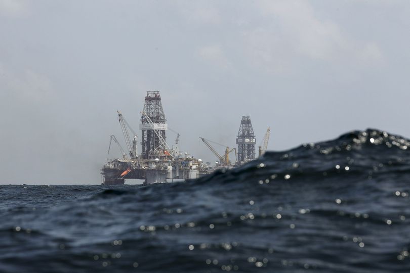 Waves partially obscure rigs drilling relief wells at the oil spill site in the Gulf of Mexico on Thursday.  (Associated Press)