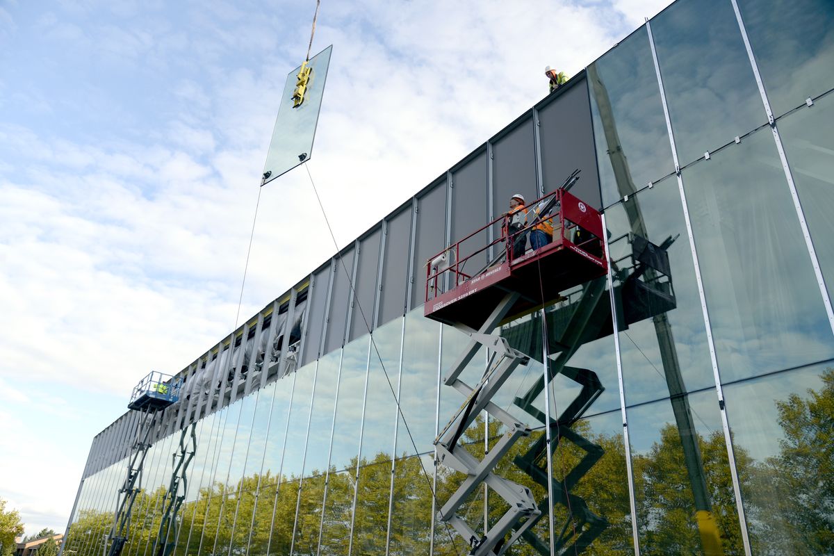 Workers lift glass panels into place at the expanded Convention Center Monday. The $50 million project expands the exhibition hall, adds a large ballroom and takes advantage of river views. (Jesse Tinsley)