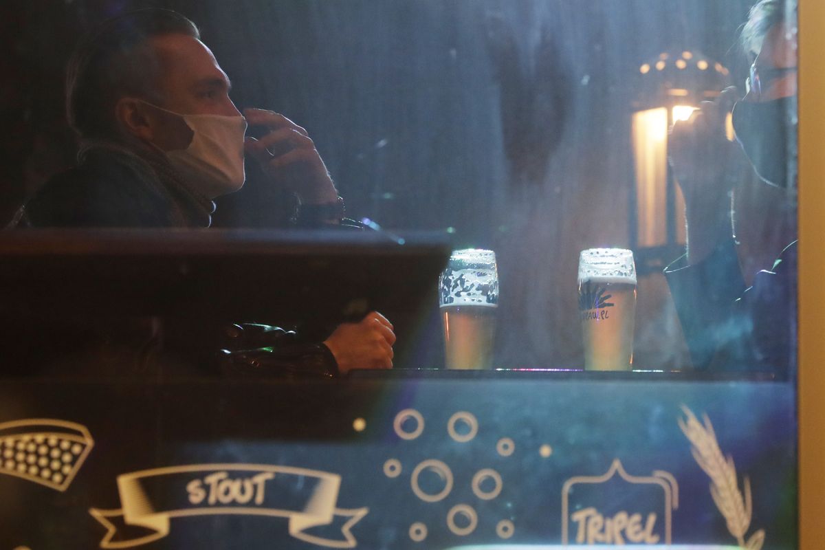 People drink beer in a bar which was open in defiance of pandemic restrictions in Warsaw, Poland, Friday March 26, 2021. Police raided the bar and arrested the owner on Friday. A raft of new pandemic restrictions take effect in Poland on Saturday to slow the spread of infection in what has become of the new global hot spot for the virus, but even earlier restrictions are being defied by some.  (Czarek Sokolowski)