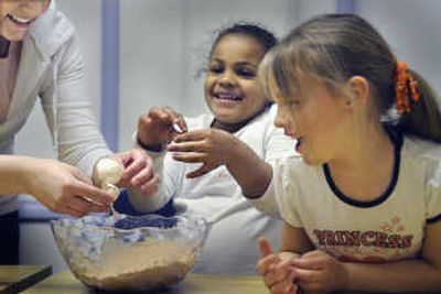 Brianne Browning, left, rescues the eggshells from the brownie mix to help Carolean Harmon, center, and Ashlynn Riese-Suires at the Northeast Youth Center kindercamp in Spokane on Tuesday.
(CHRISTOPHER ANDERSON / The Spokesman-Review)