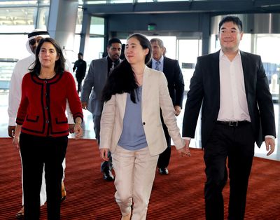 Grace, center, and Matthew Huang, right, walk to their departure gate with U.S. Ambassador to Qatar Dana Shell Smith, left, at the Hamad International Airport in Doha, Qatar, on Wednesday. (Associated Press)