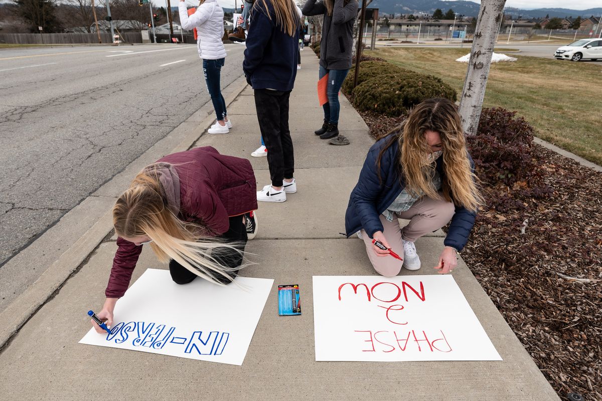Ella Lamoreaux, 15, left, and her mother, Jennifer, make signs on the sidewalk Tuesday in front of Central Valley High School for the “March for More.” (Colin Mulvany/THE SPOKESMAN-REVIEW)