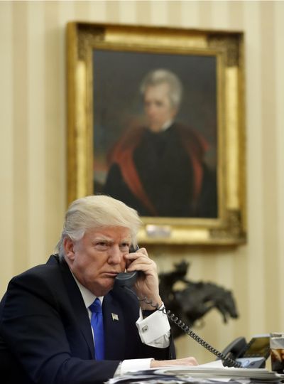 President Donald Trump speaks on the phone in the Oval Office Saturday, with a portrait of Andrew Jackson behind him. (Alex Brandon / AP)