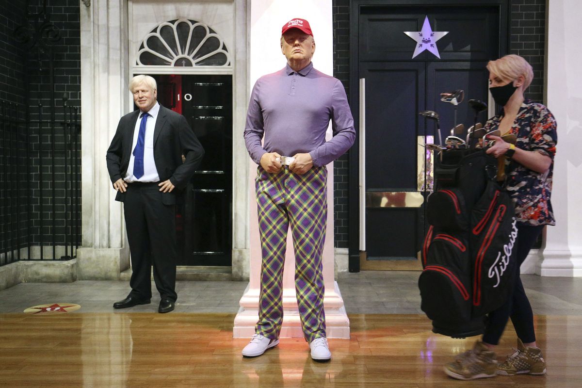 A member of the Madame Tussauds studios team places a set of golf clubs next to a wax figure of US President Donald Trump which has been re-dressed in golf wear following the 2020 US presidential election, in London, Wednesday, Nov. 4, 2020. Joe Biden was elected Saturday, Nov. 7, 2020 as the 46th president of the United States, defeating President Donald Trump in an election that played out against the backdrop of a pandemic, its economic fallout and a national reckoning on racism.  (Jonathan Brady)