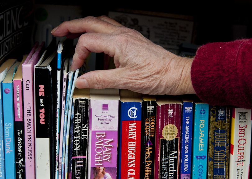 Mary Maxfield browses books in the Little Free Library in her front yard. (Dan Pelle)
