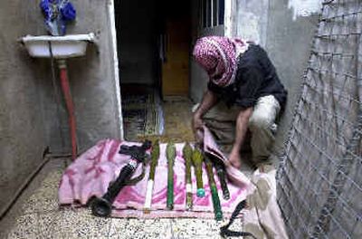 
A masked gunman collects his ammunition at his home in Sadr City on Sunday. Militiamen loyal to Muqtada al-Sadr have begun handing over weapons to Iraqi police. 
 (Associated Press / The Spokesman-Review)