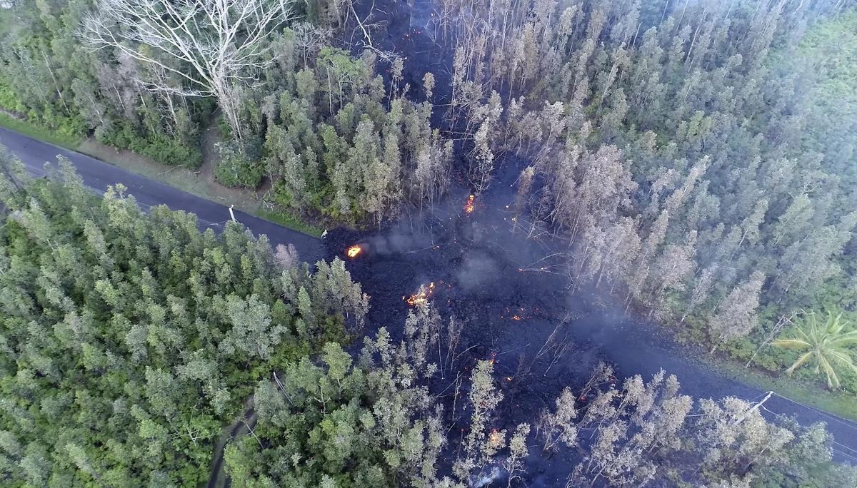 In this still frame taken from video, lava flows over a road in the Puna District as a result of the eruption from Kilauea Volcano on Hawaii’s Big Island Friday, May 4, 2018. The eruption sent molten lava through forests and bubbling up from paved streets and forced the evacuation of about 1,500 people who were still out of their homes Friday after Thursday’s eruption. (Byron Matthews / Associated Press)