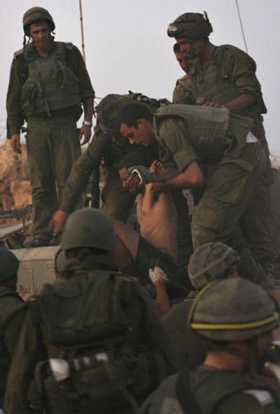 
An injured Israeli soldier is helped from the top of an armored military vehicle Wednesday after crossing the border from Lebanon into Israel.
 (Associated Press / The Spokesman-Review)