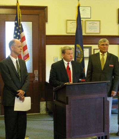 Idaho Attorney General Lawrence Wasden, center, speaks in Boise on Tuesday; at left is his consumer protection bureau chief, Brett DeLange; at right, Idaho Health & Welfare Director Dick Armstrong. (Betsy Russell)