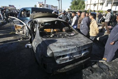 Iraqis stand at the site of a car bombing in the northern Baghdad Shiite neighborhood of Kazimiyah on Saturday. At least 22  people were killed and dozens more were wounded in the blast, the U.S. military said.  (Associated Press / The Spokesman-Review)