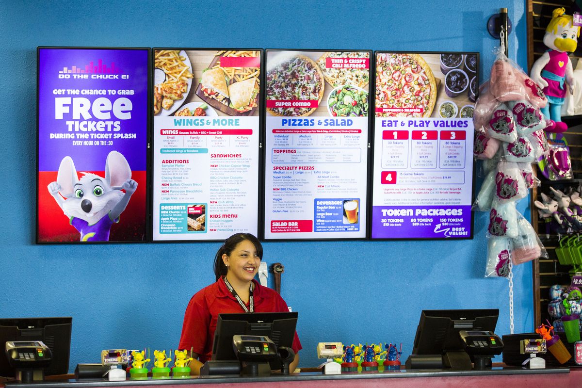 Employee Adrianna Morales stands at the counter in front of a new digital menu board at Chuck E. Cheese’s on Wednesday in Irving, Texas.