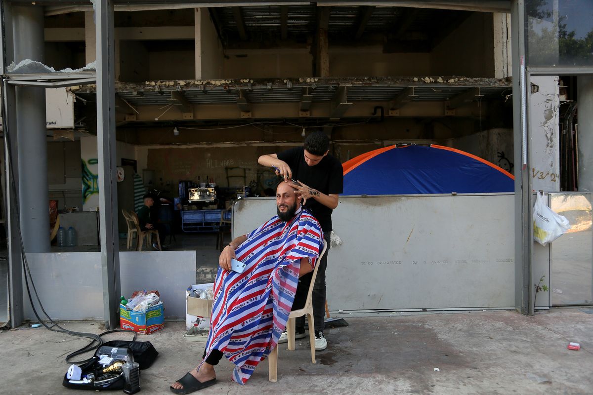 A Lebanese, who escaped his southern village, gets his hair cut at an open air barber outside SkyBar nightclub, one of the most famous nightlife hot spots in Beirut, that became a sanctuary for hundreds of people.  (Marwan Naamani/ZUMA Press Wire/TNS)