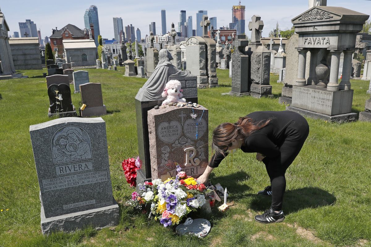 Sharon Rivera adjusts flowers and other items left at the grave of her daughter, Victoria, at Calvary Cemetery on May 10, 2020, in New York, on Mother’s Day. Victoria died of a drug overdose in Sept. 22, 2019, when she just 21 years old.  (Kathy Willens)