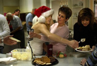 
Mitch Belyea, left, and Lynn Gregory cross paths as they serve a free Christmas meal at Valley Bowl in Spokane Valley on Sunday. 
 (Liz Kishimoto / The Spokesman-Review)