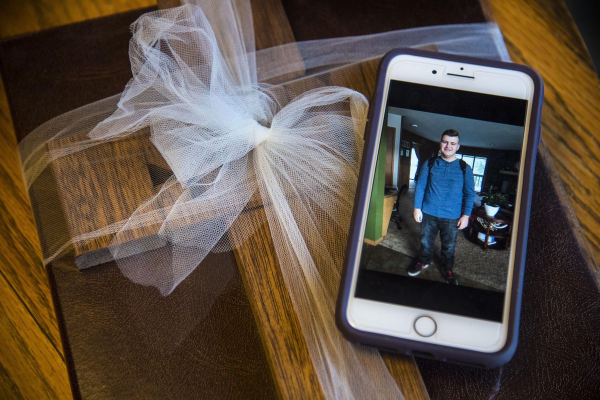 An image of Sam Strahan on his mother’s phone sits atop a a scrapbook of remembrances and a wooden cross from his friends. The picture was taken on the first day of school, Wednesday, Aug. 30, 2017. (Dan Pelle / The Spokesman-Review)