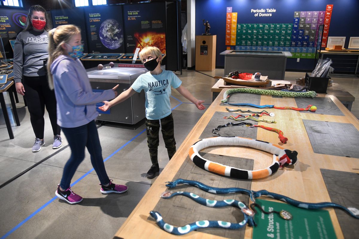 Lincoln Lindell, 7, center, presents his name spelled out in toy snakes from the gift shop to his sister, June, 10, during an assignment for Curriculum Camp, Friday, Sept. 25, 2020, at Mobius in downtown Spokane. Facing financial pressure caused by COVID-19, Mobius has combined its science museum and children’s museum under a single roof, now called the Mobius Discovery Center. It will close its former location in River Park Square. Mobius educator Tiniya Dixon watches at left.  (DAN PELLE/THE SPOKESMAN-REVIEW)