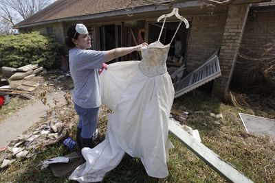 Amanda Cavazos hangs her sister’s wedding dress after it was found in the debris at her mother’s badly damaged home Wednesday in Galveston, Texas.  (Associated Press / The Spokesman-Review)