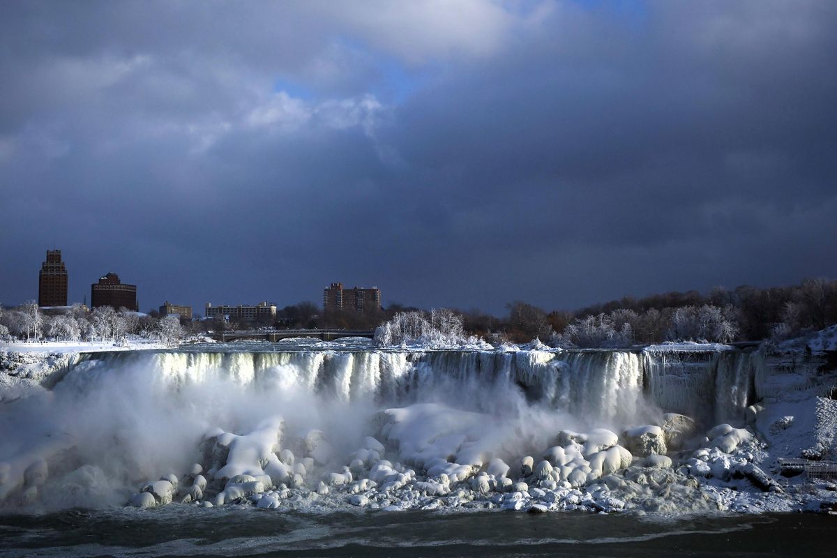 Water flows over the American Falls as ice forms in this view from the Canadian side in Niagara Falls, Ont., Tuesday, Jan. 2, 2018. Almost every year frigid temperatures transform the falls into an icy winter wonderland when the mist is blown back, freezing on the landscape. (Aaron Lynett / AP)