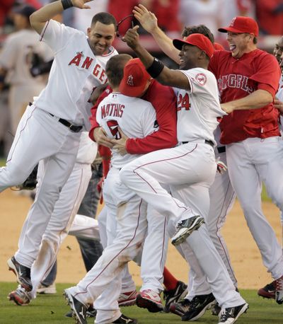 Jeff Mathis (5) is mobbed by his teammates after his double scores the winning run in the ALCS Monday. (Associated Press / The Spokesman-Review)