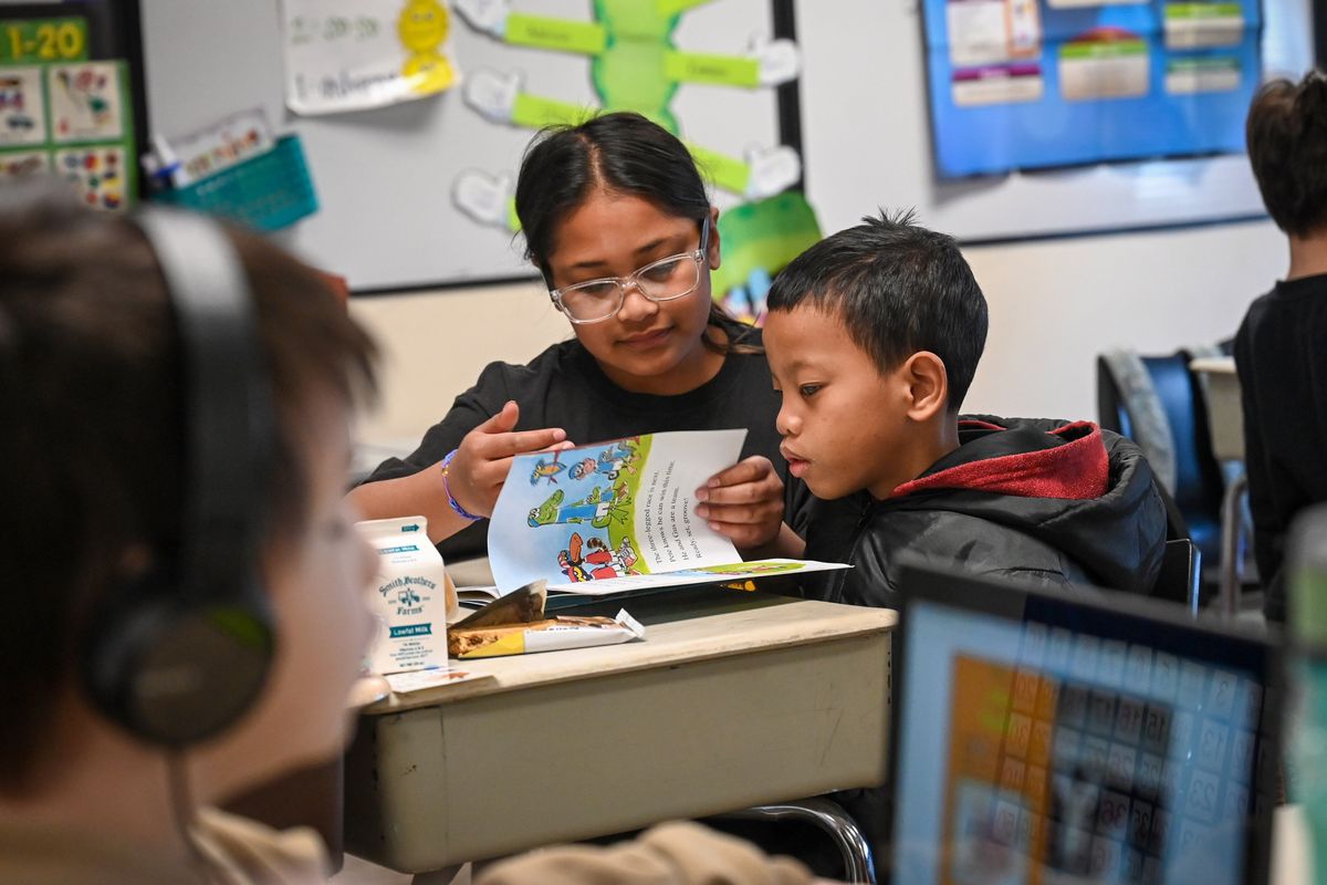 Sheila Ceaser, a Frances Scott Elementary School sixth-grader and Education Club member, works in Sarah Hawkes’ first-grade class with student BJ Arelong on April 13 in Spokane. They were reading “Pete the Cat Rocking Field Day.”  (DAN PELLE/THE SPOKESMAN-REVIEW)