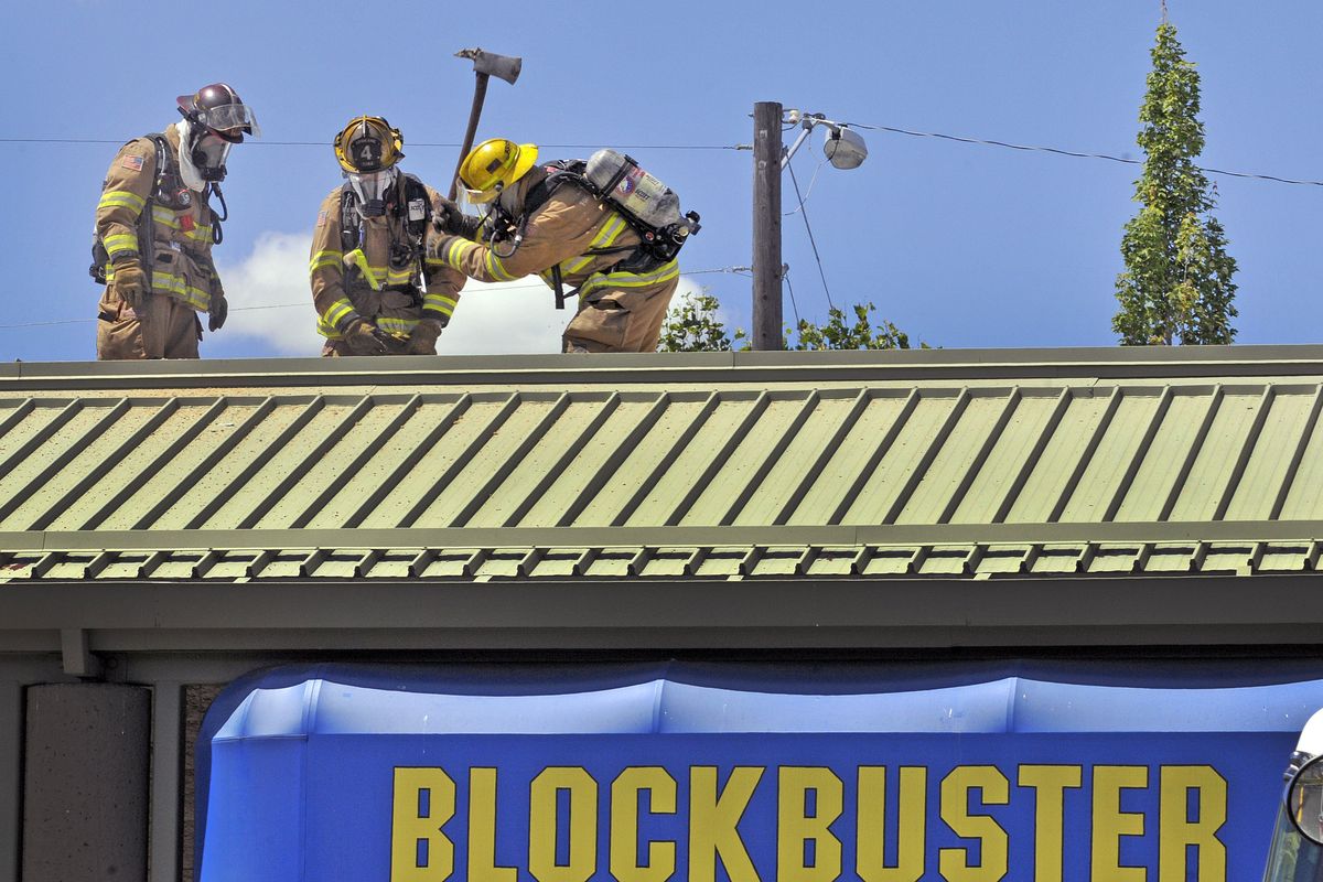 Spokane firefighters chop through the roof of the Blockbuster Video Store at 29th and Southeast Blvd. to get at a stubborn fire Tuesday July 6, 2010.   (Christopher Anderson / Spokesman-Review)