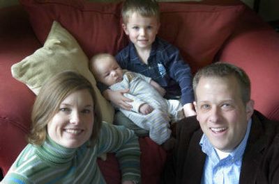 
Five-year-old Eli holds his 8-week-old brother Owen as they sit with their parents Shawna and Joshua Armstrong on Tuesday at their Spokane home. 
 (Christopher Anderson / The Spokesman-Review)