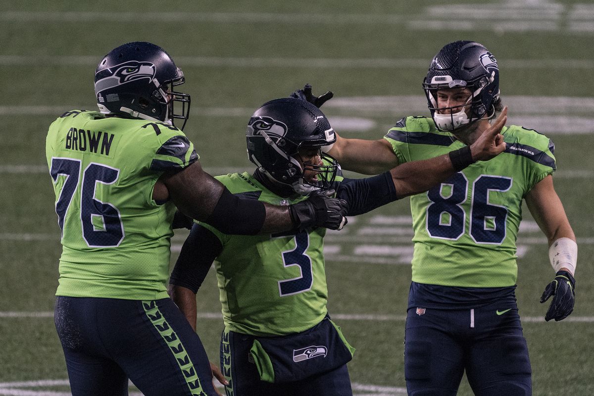 Seattle Seahawks quarterback Russell Wilson (3) is congratulated by teammates offensive lineman Duane Brown (76) and tight end Jacob Hollister after throwing the game winning touchdown during the second half of an NFL football game against the Minnesota Vikings, Sunday, Oct. 11, 2020, in Seattle. The Seahawks won 27-26. (Stephen Brashear)