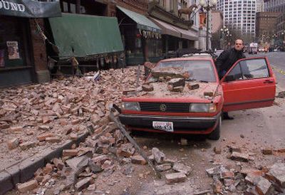 
Paul Riek checks damage to his vehicle after the top half of a nearby building collapsed in downtown Seattle during the Nisqually earthquake on Feb. 28, 2001. 
 (file Associated Press / The Spokesman-Review)