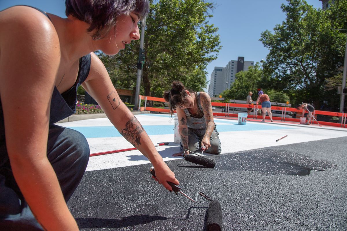 Esme Hunt, left, and Susan Webber pitch in to paint the intersection of Spokane Falls Boulevard and Howard Street, just outside Riverfront Park.  (Jesse Tinsley/THE SPOKESMAN-REVIEW)