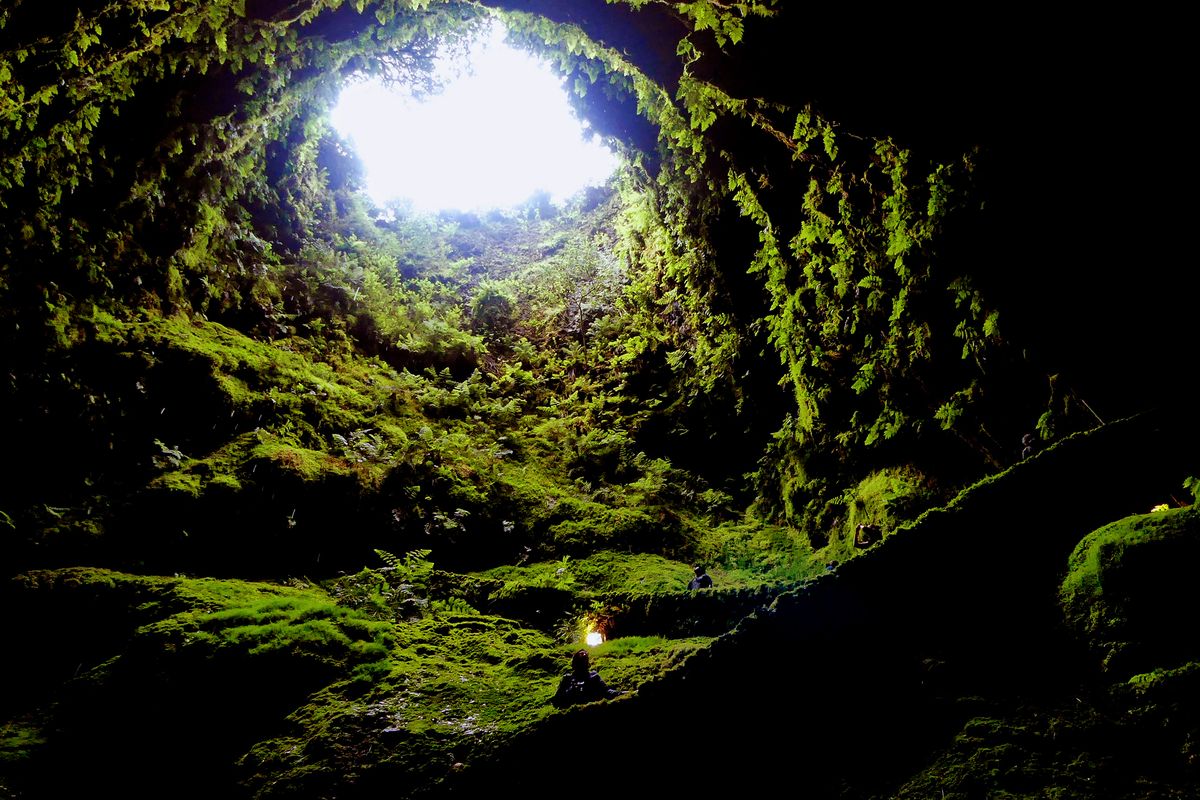 Visitors hike down the lava tube in the Algar do Carvão volcanic cave on Terceira in the Azores.  (Bob Drogin/For the Washington Post)