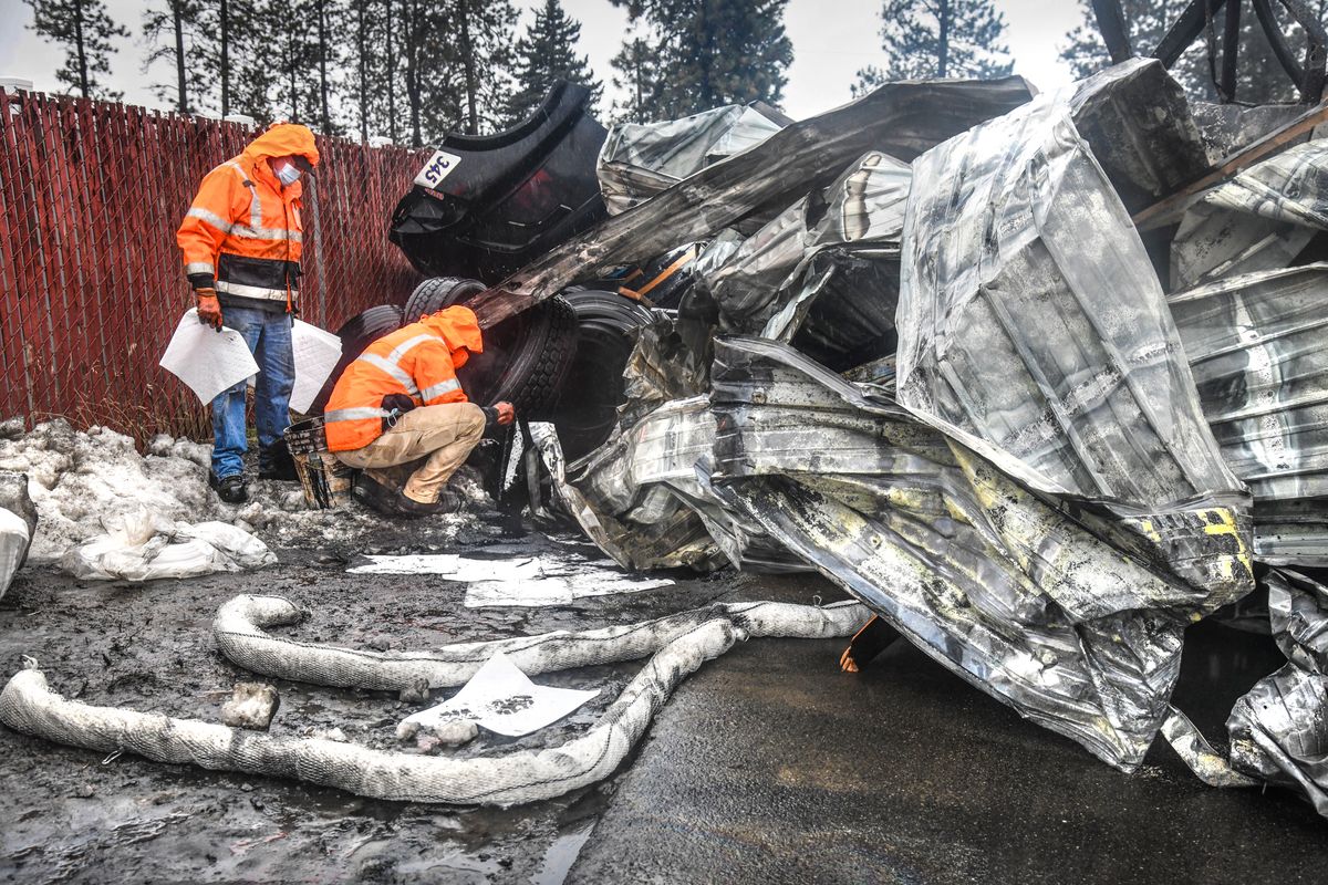 Kipp Silver, left, and Weston Boardman, of Able Clean-up Technologies Inc., place pads and booms to soak up and stop motor oil from spreading at the site of a fire at a building holding commercial vehicles Tuesday morning at Victory Transportation on West Thorpe Road.  (DAN PELLE/THE SPOKESMAN-REVIEW)