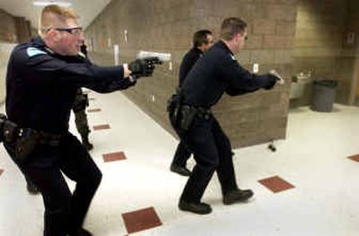 
Carrying a plastic gun, Officer Jason Dewitt, left, of the Post Falls Police Department follows fellow officers around a corner in the halls of Post Falls High School during training Friday. 
 (Jesse Tinsley / The Spokesman-Review)