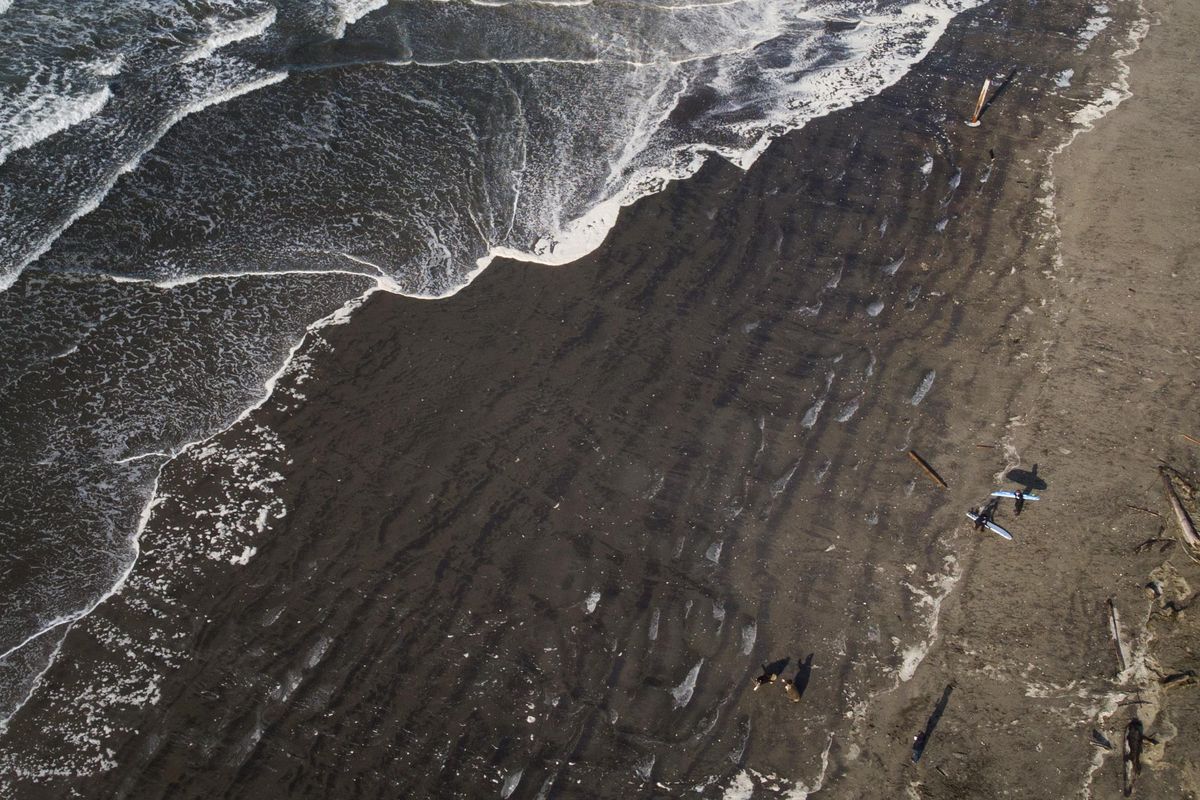 Surfers head toward the Nov. 24, 2019 near Westport, Wash. Using wet suits, boots and gloves, it